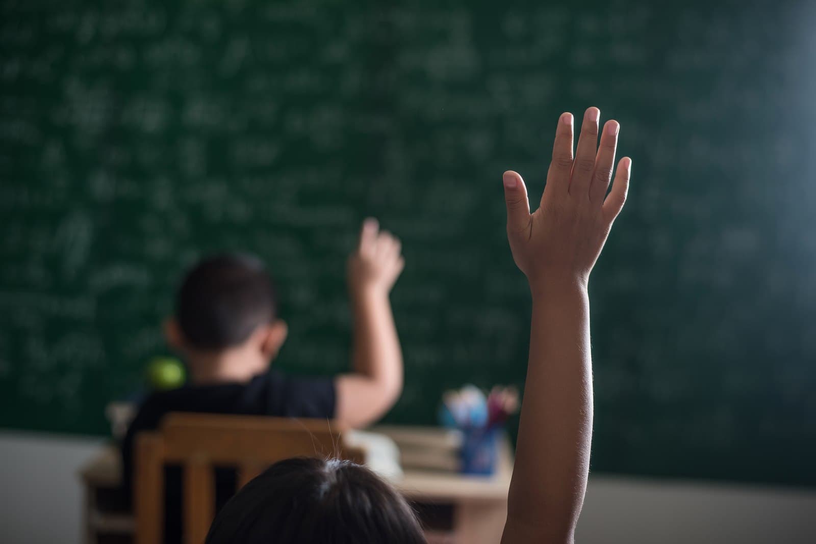 Estudante levantando a mão para fazer uma pergunta em sala de aula